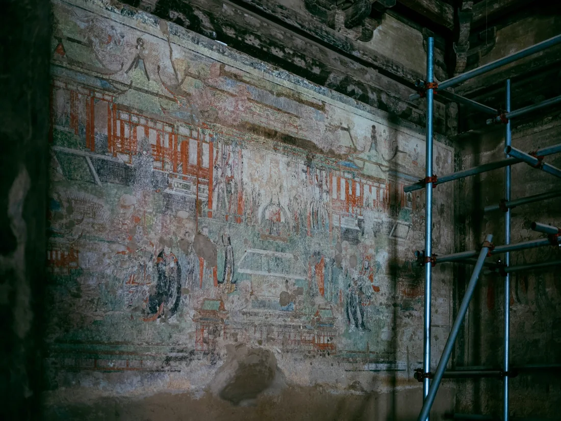 Pintura mural antigua sobre un muro desgastado con andamio delante durante los trabajos